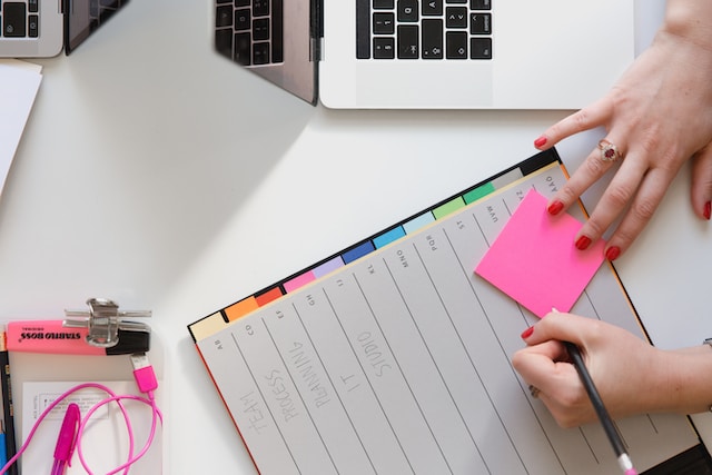 photo of a hand over a planner with sticky notes